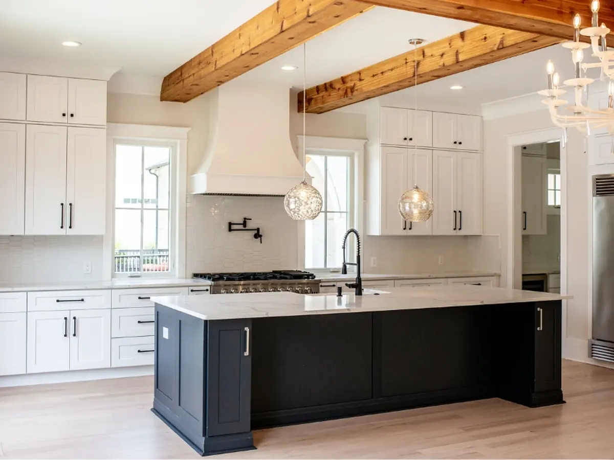 White kitchen with a navy blue island, white stone countertop and glass globe pendants