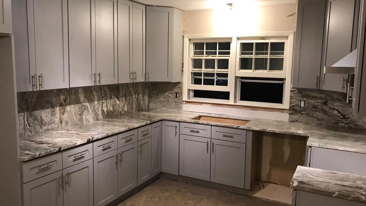 Granite countertops with a full stone backsplash on gray cabinets