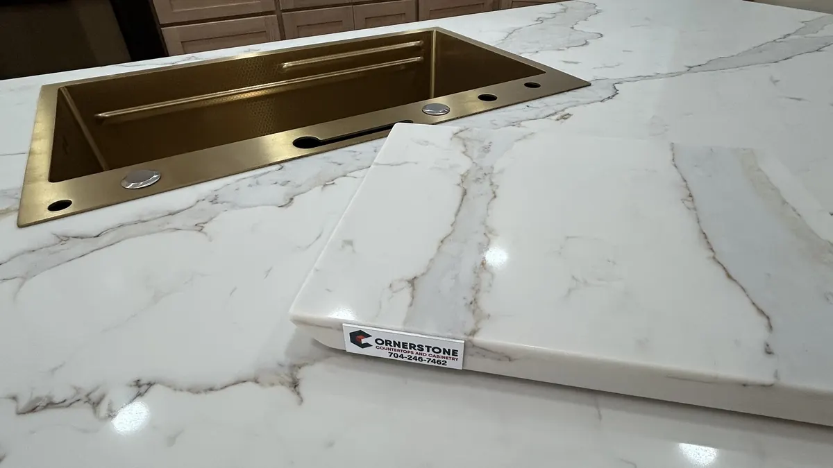 Calacatta-style quartz with gray and gold veins around a brass sink