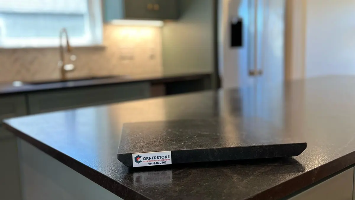 Kitchen with a dark leathered stone countertop and green cabinets