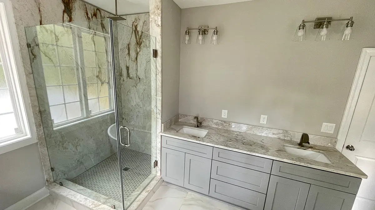 Shower with stone wall panels and a glass enclosure