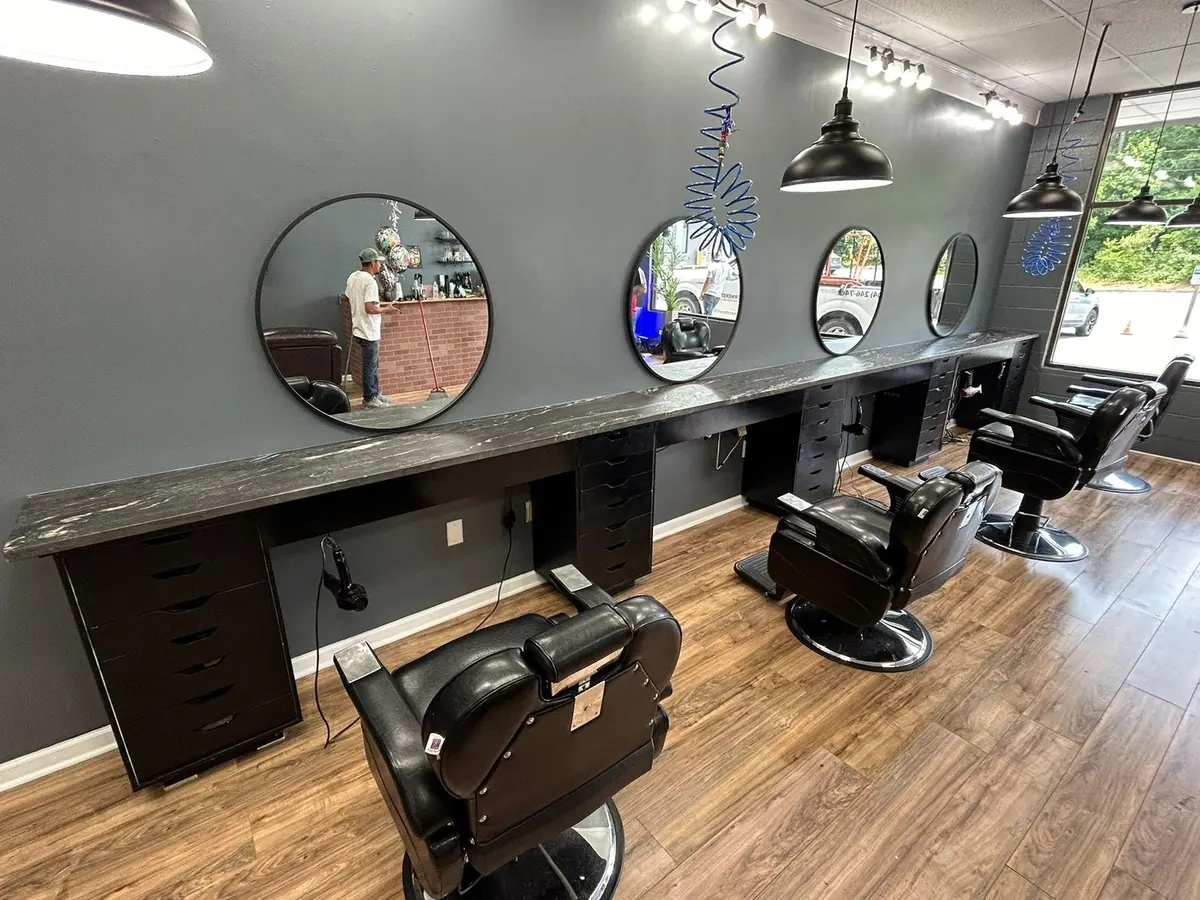 Barbershop stations with dark stone countertops and round mirrors