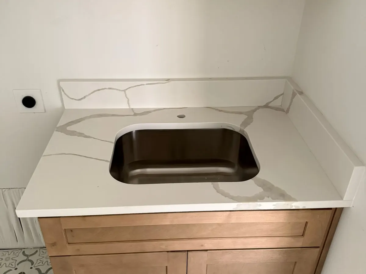 Undermount sink set into a new stone countertop before the plumber reconnects the faucet