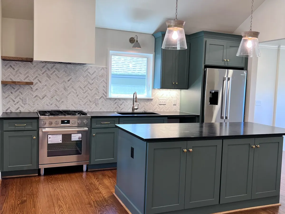 New green shaker cabinets with a black stone countertop island
