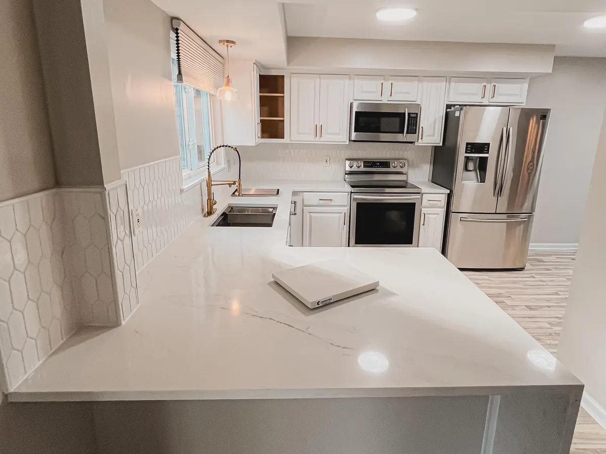 White L-shaped kitchen with a waterfall countertop end and white cabinets