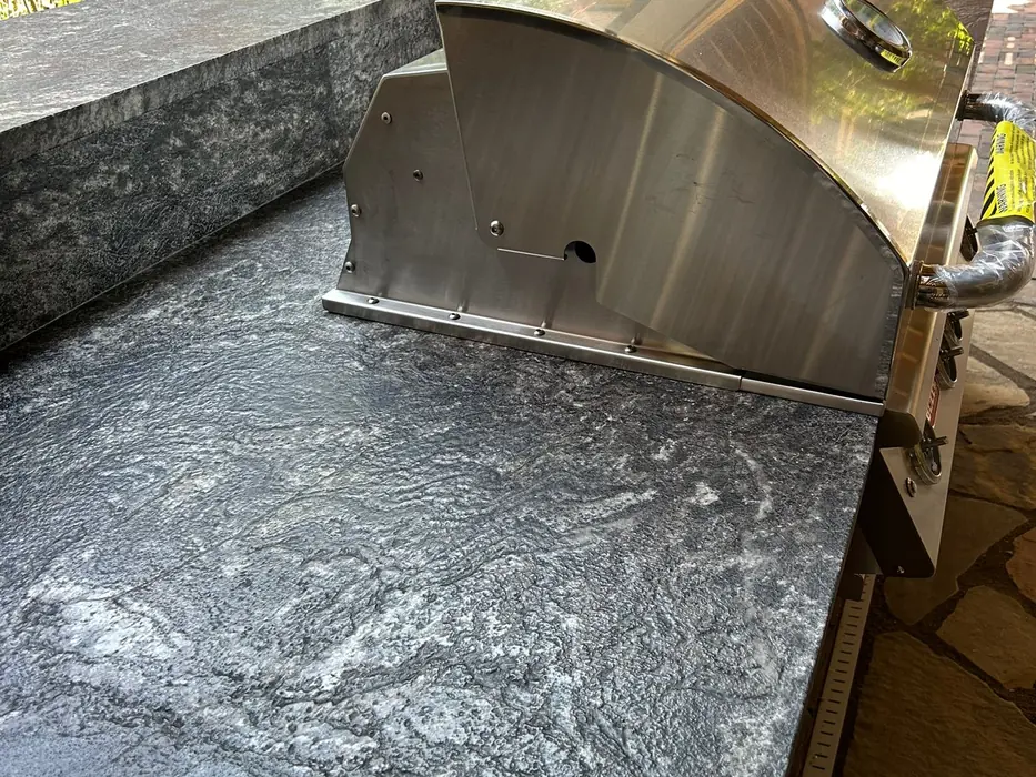Outdoor kitchen with a stone countertop around a built-in grill