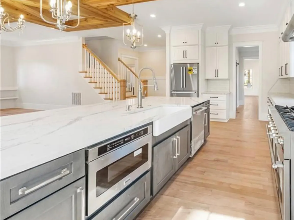 White veined stone island with a farmhouse sink across from a professional range