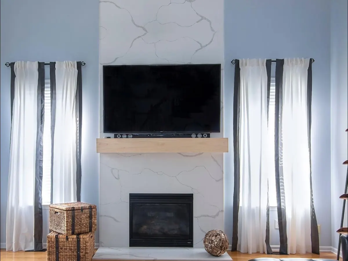 Full-height white stone fireplace surround with gray veining and a wood mantel